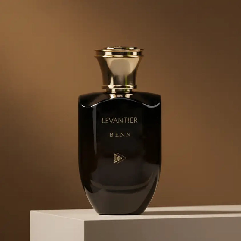 Elegant black glass perfume bottle with a gold-toned cap and embossed branding.