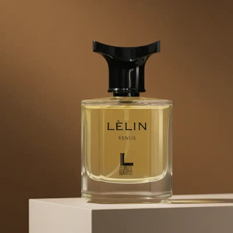 A sleek, transparent glass perfume bottle with a black cap and gold-tinged liquid inside.